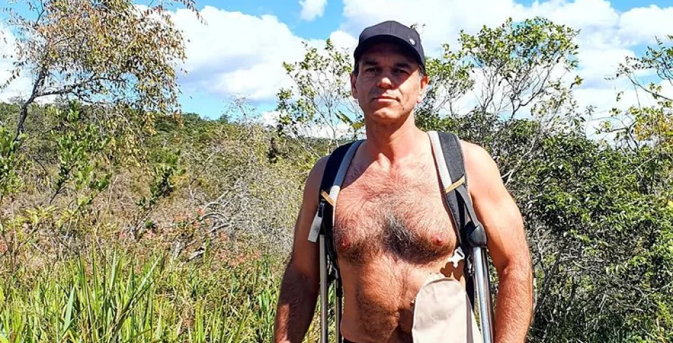 muž s batohom a klobúkom stojaci na poli